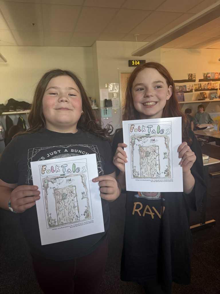 The illustrators of the book cover holding up their copies of the book.