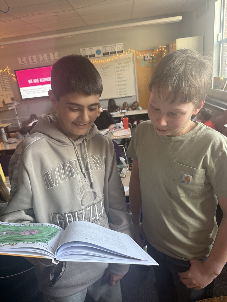 Two students reading a book together. 