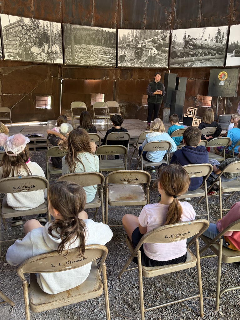 Students are watching a presenter speak about bats in Montana.