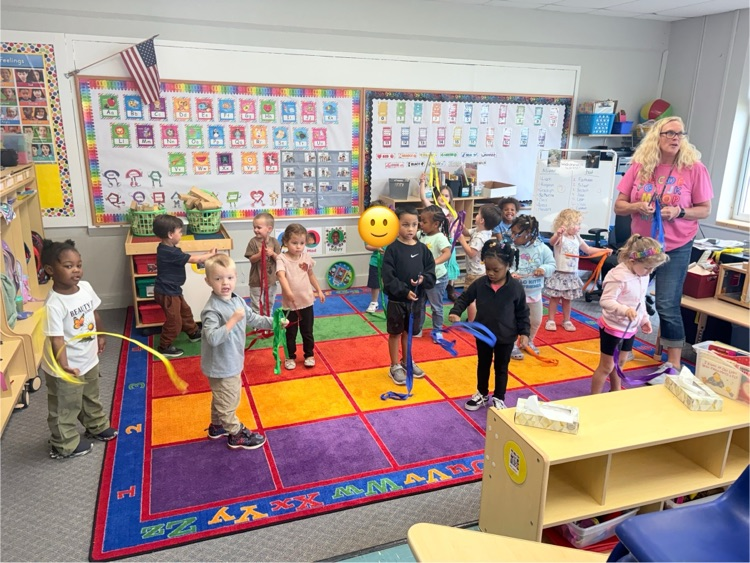 children dance to music with ribbons in their hands