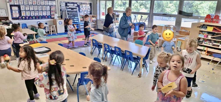 Kids march around the classroom with various musical instruments