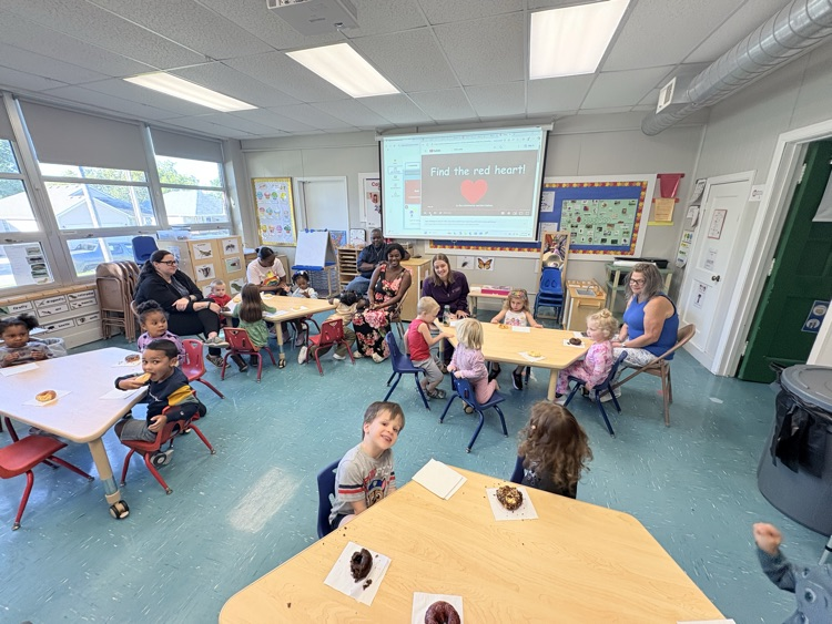 kids and adults eat donuts together in a classroom