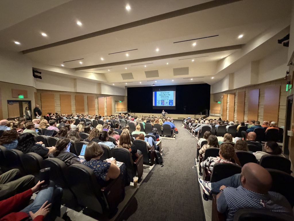 USD 204 teachers and staff seated in an auditorium listening to a professional development presentation by Todd Whitaker.