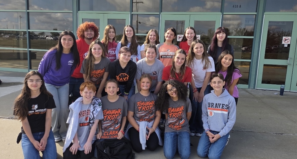 A group of Bonner Springs High School and Clark Middle School FCCLA students gather outside the school entrance for a group photo, smiling in their school shirts.