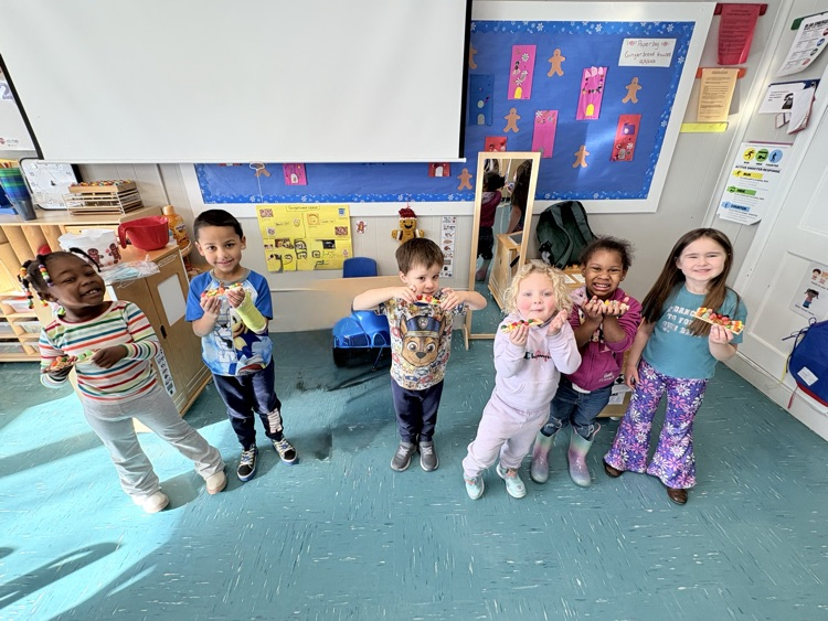 kids hold up gingerbread houses