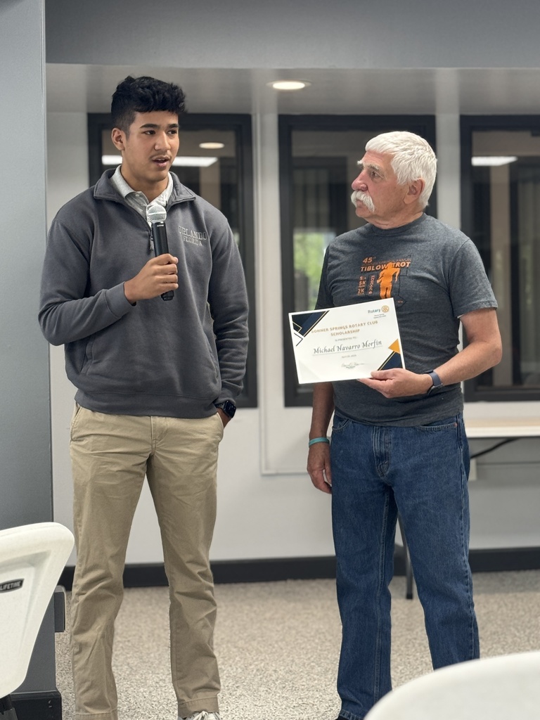 A man holds a microphone while another man holds a certificate and stands next to him.