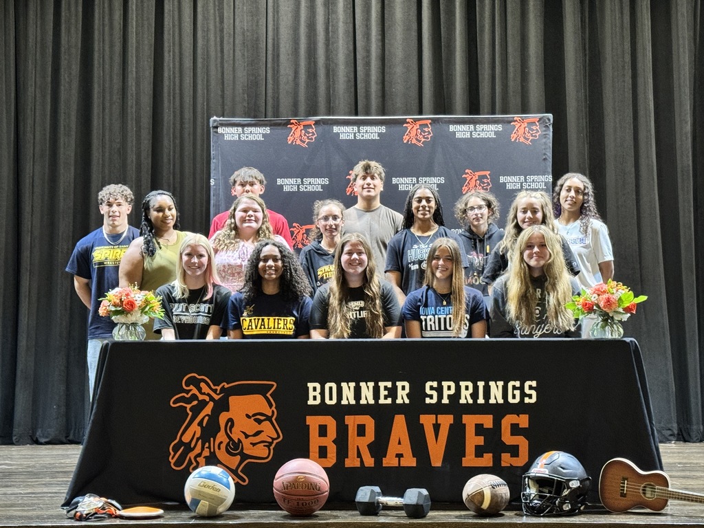A group of young athletes poses behind a table with sports equipment and a banner that reads "Bonner Springs Braves."
