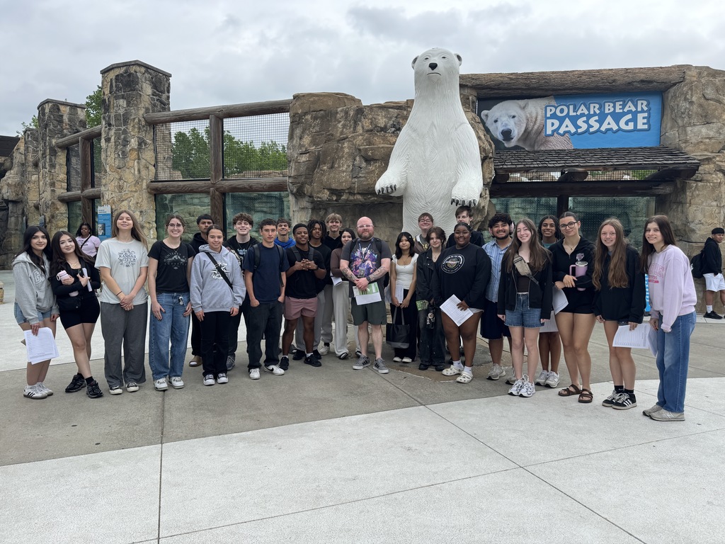A group of people poses for a photo in front of a Polar Bear Passage exhibit at the KC Zoo.