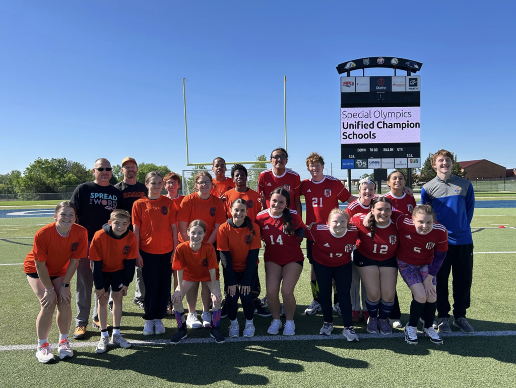 A group of young people in red jerseys posing for a photo on a football field.