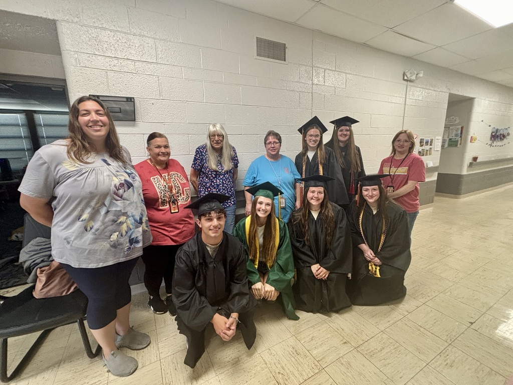 A group of people in a hallway, some in caps and gowns, posing for a photo.
