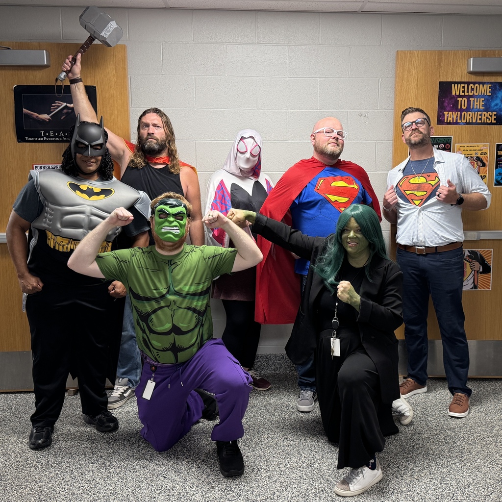A group of people in superhero costumes posing for a photo. A man in green crouches in the front.