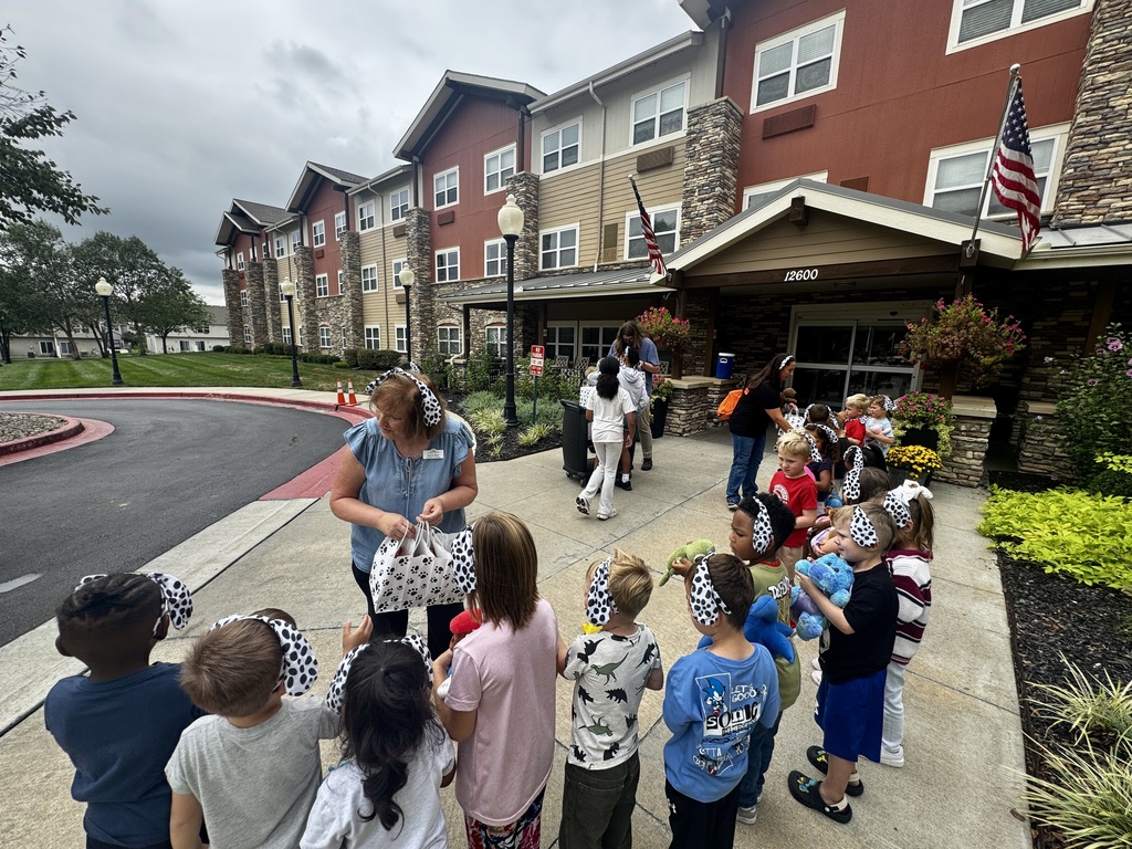 A group of children with blindfolds and hats are gathered in front of a building.