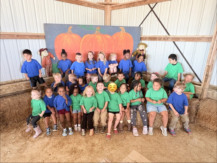 children sitting on hay bales at a pumpkin patch