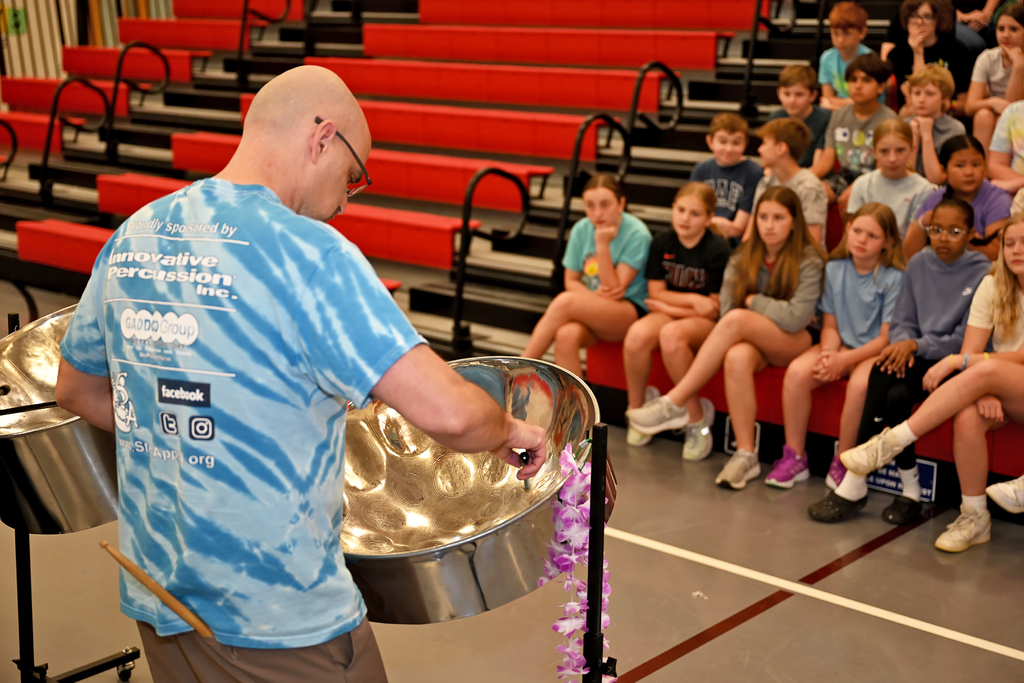 students watching man playing steel drums