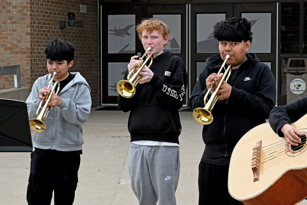 Three young musicians playing trumpets