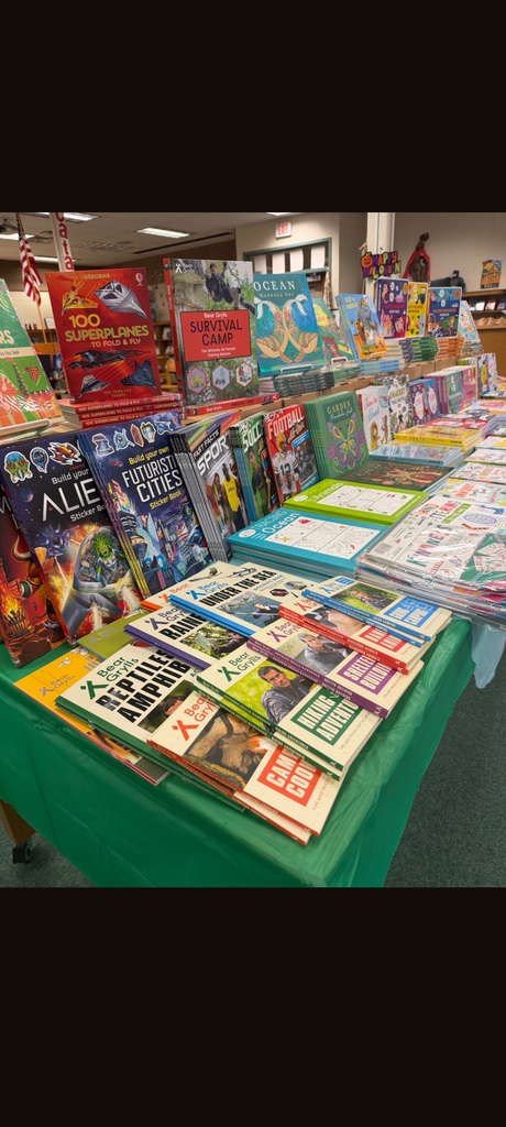 Books on a table in a library, including "ALIEN" and "REPTILE AMPHIBS" series. Colorful books with illustrations.