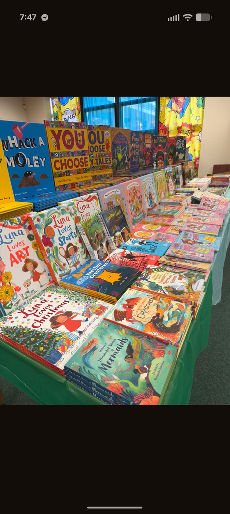 Books on display on a table with a green tablecloth, arranged in rows and facing the camera.