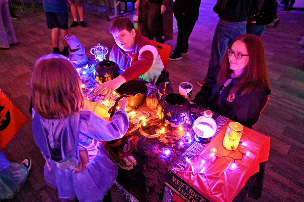 A table with lights and decorations, a girl in a dress and a boy in a jacket.