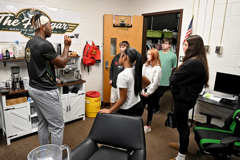 adult and students staning in front of coffee maker