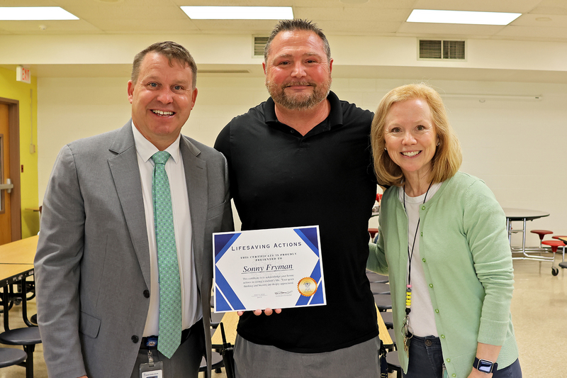 Three adults with a certificate