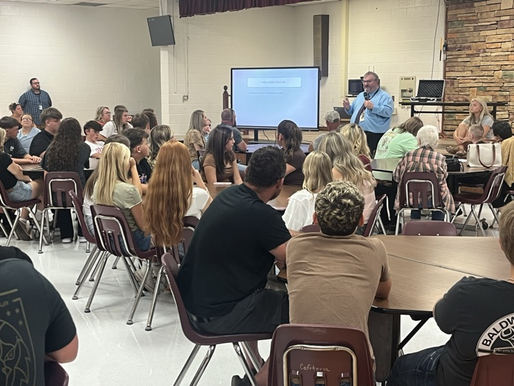 Parents and students listen as a school principal presents school rules