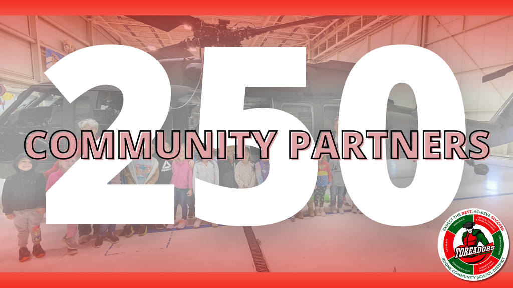 faded background image of students standing in front of a military helicopter inside a hangar. Large bold white numbers "250" are centered with the words "Community Partners" written across in black outlined text. The Boone Community School District logo featuring a Toreador mascot is in the bottom right corner.