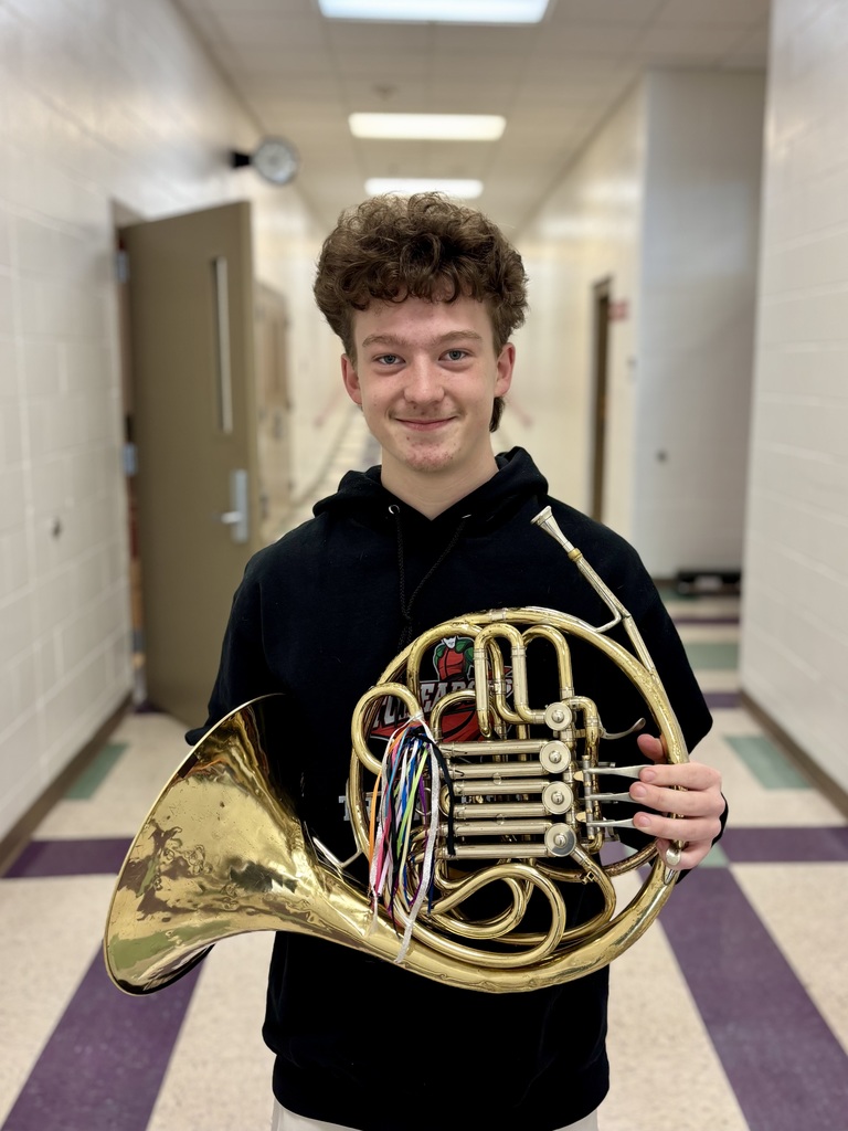 one male student holding a horn musical instrument