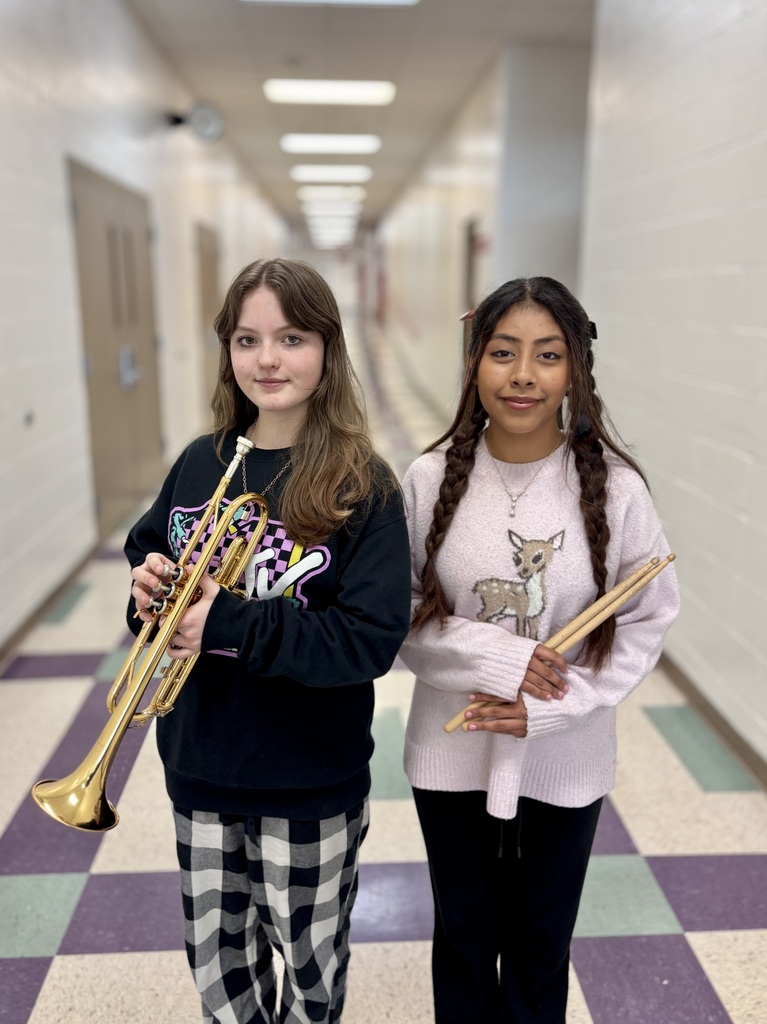 two female middle school students holding music instruments