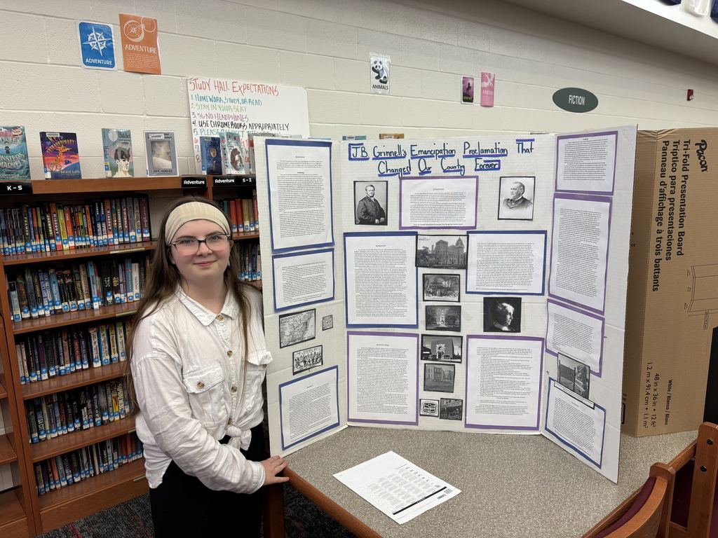 a 6th grade Excel student standing by their completed research project