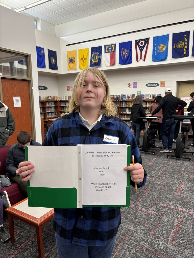 a 6th grade Excel students holding their research project in front of them