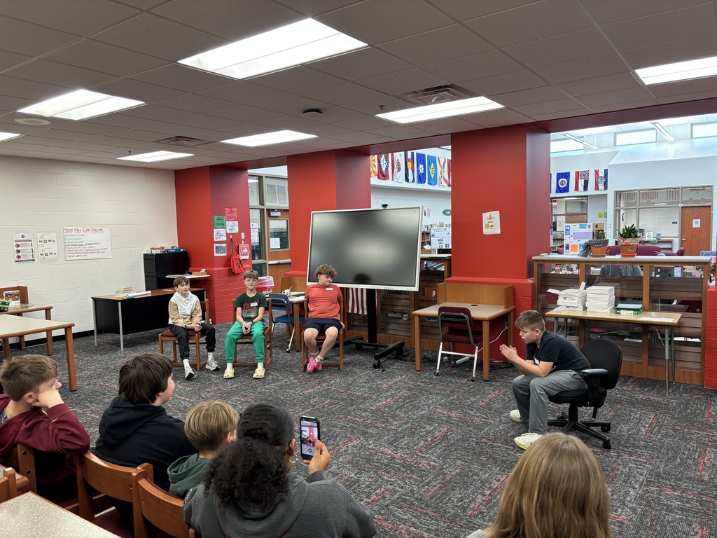 four 6th grade Excel students presenting their research project in front of an audience