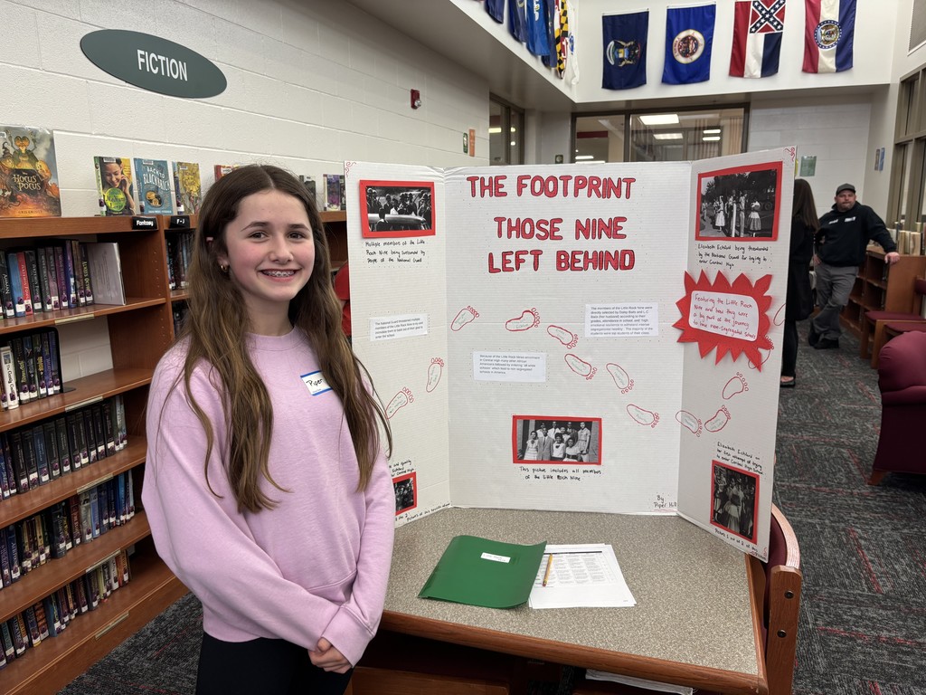 a 6th grade Excel students standing by her research project board on "the footprint of those nine left behind"