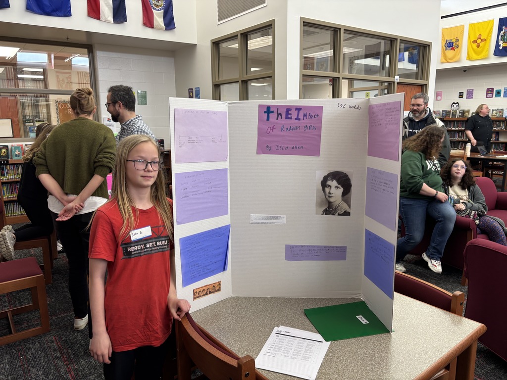 a 6th grade Excel student standing by their research project board