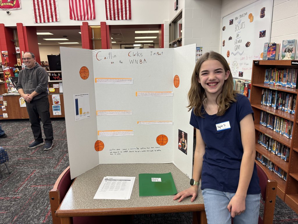 a 6th grade Excel student standing by her research project board about Caitlin Clark in the WNBA