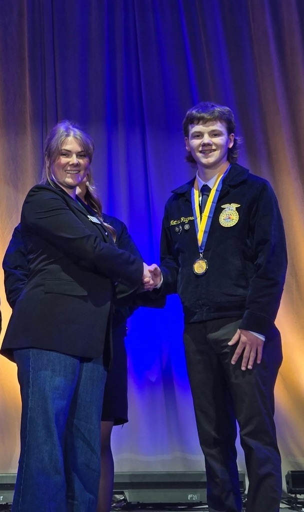 Matthew Fitzgerald on stage shaking another person's hand.