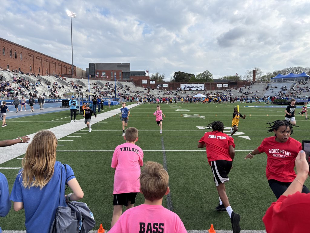 Boone students in pink shirts running the relay on the football field at the Drake Stadium.