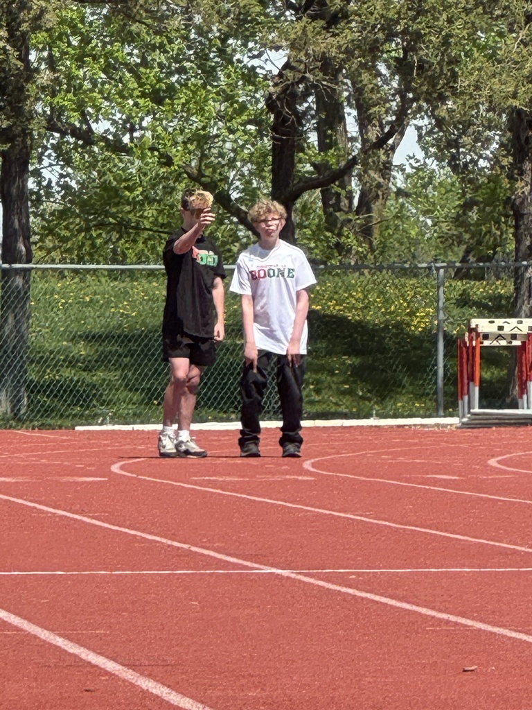 Boone student standing on a track conversing with another student.