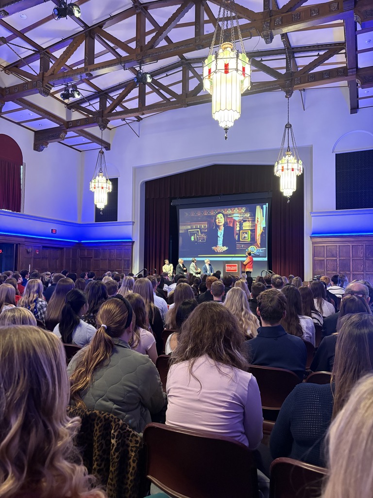 Room full of people sitting listening to a presentation.