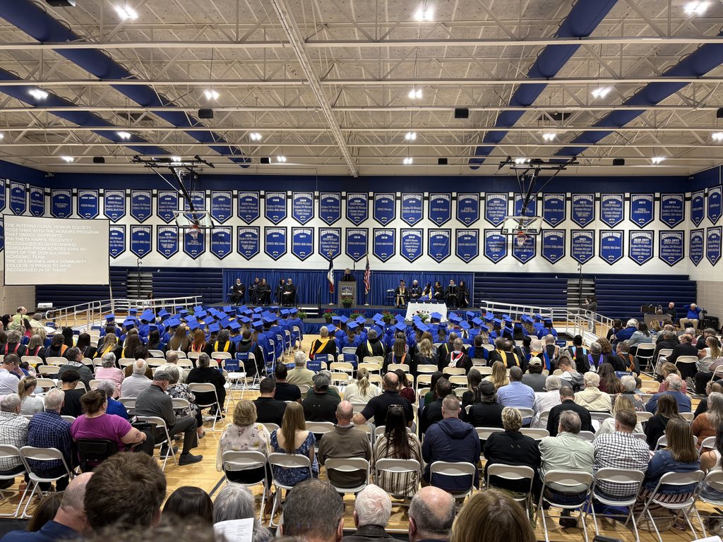 Gym filled with people sitting in chairs looking at the stage for a graduation ceremony.