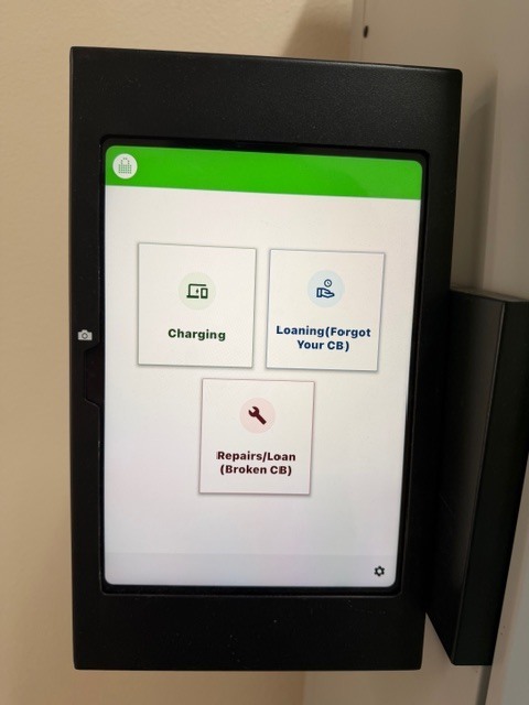 Black frame on wall with a tablet screen showing three icons, one with a plug, one with a wrench, and one with a building.
