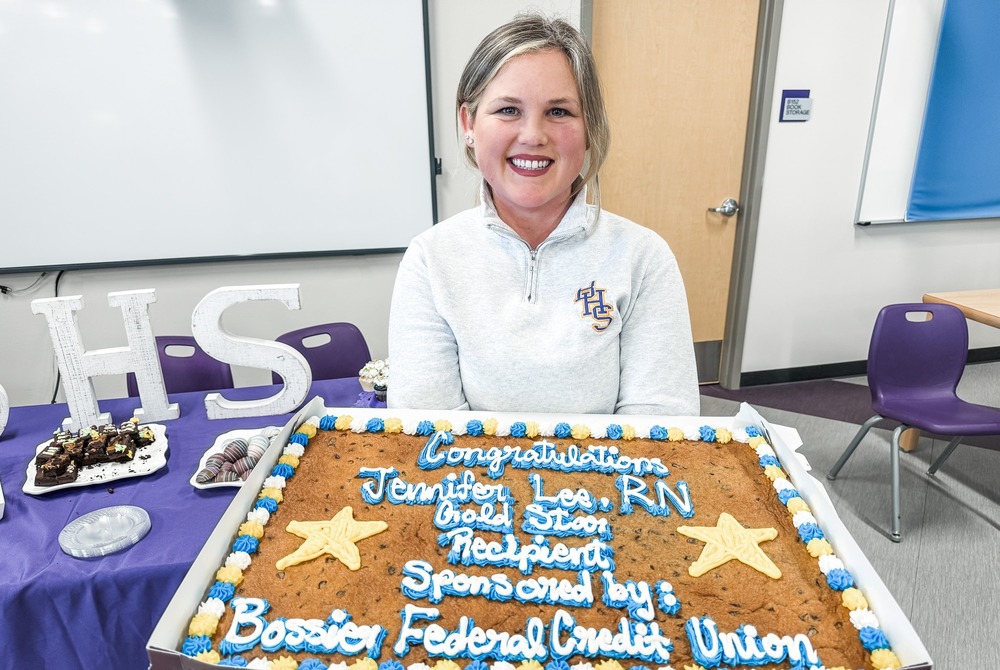 Jennifer Lee is holding a cookie cake that says "Congratulations Jennifer Lee, RN, Gold Star Recipient, Sponsored by Bossier Federal Credit Union