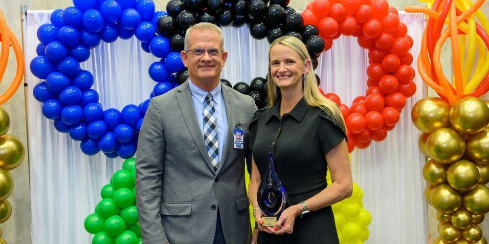 Dr. Vicki Younger, holding her Spirit of Excellence Award, poses with Superintendent Jason Rowland