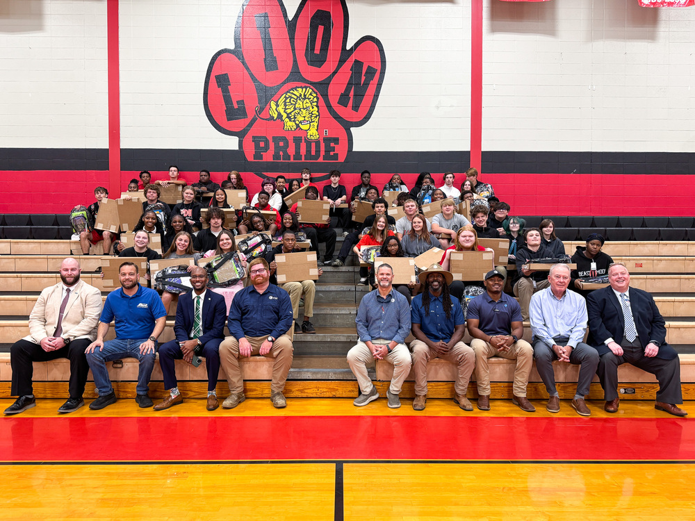 Group photo of students holding laptop with AT&T representatives on the front row