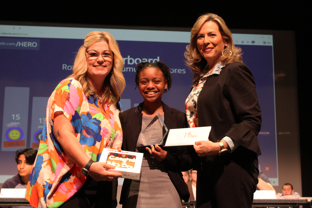 Civics Bee winner Kamilya Woodrow is in the center of the photo holding a plaque. Bossier Chamber representatives are pictured on either side of her. 