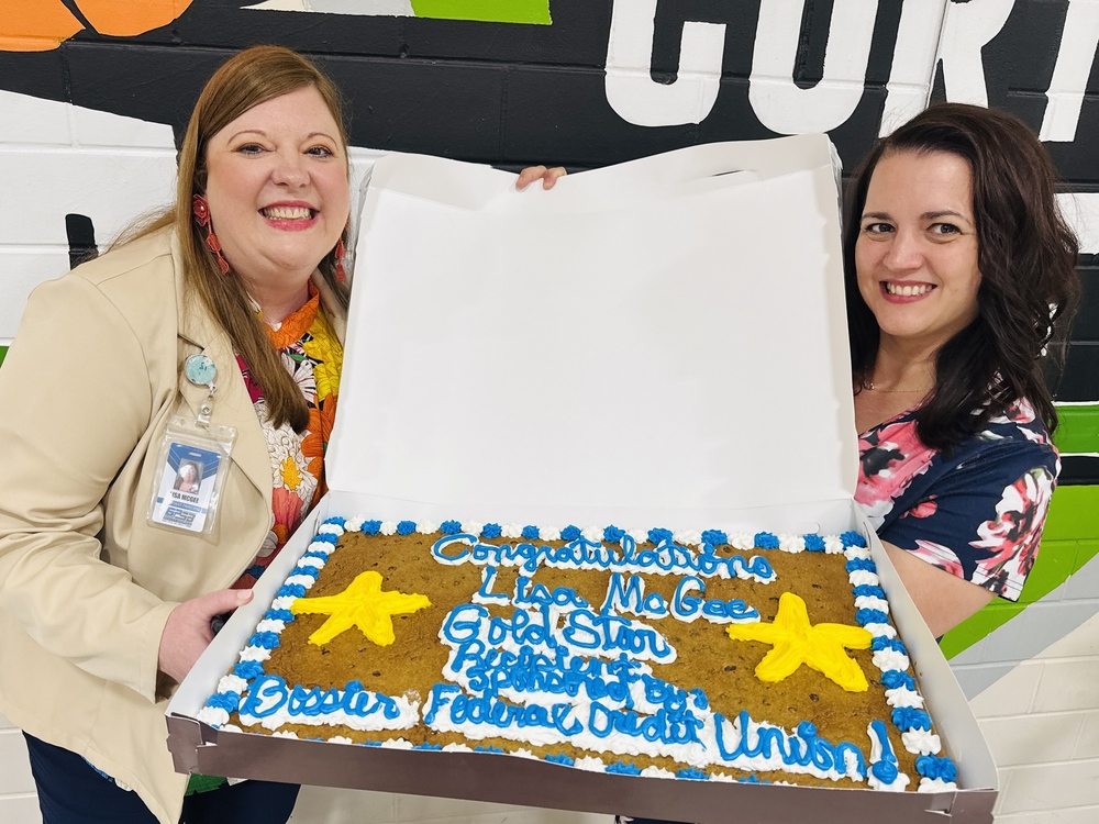 Photo of Gold Star Winner Lisa McGee on left, holding a giant cookie cake, with Bossier Federal Credit Union representative on the right