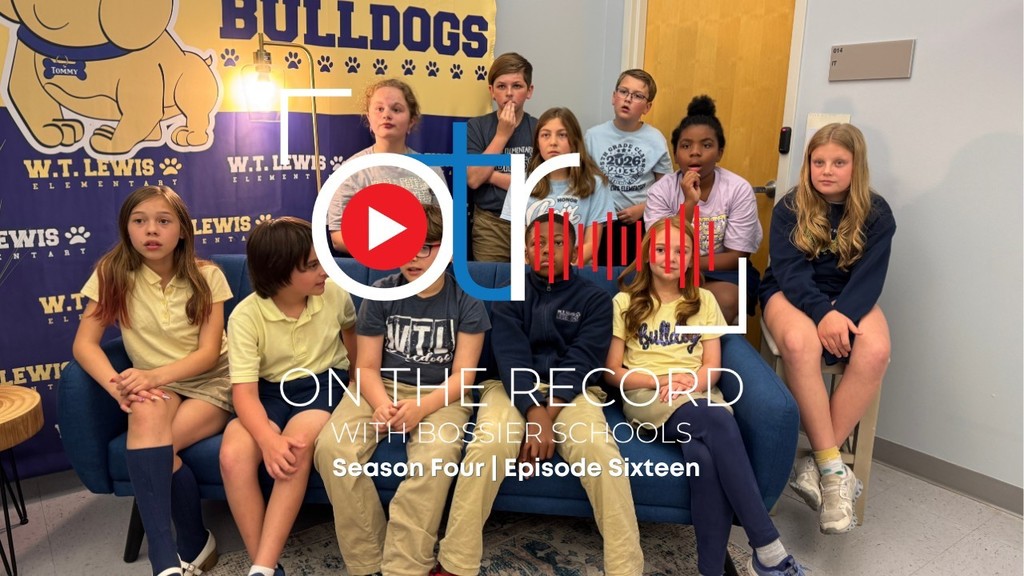 group photo of the WT Lewis Bulldog Broadcasters seated in front of a large Bulldog poster. 