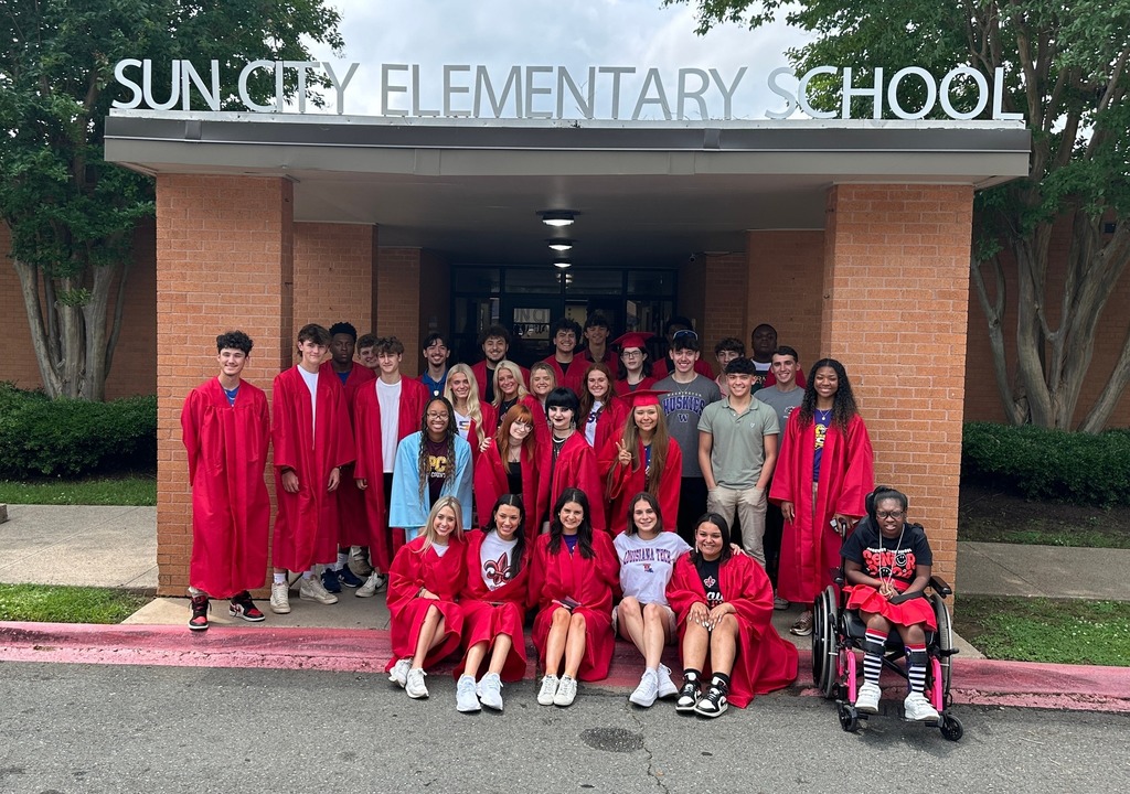 graduates in red gowns standing in front of Sun City Elementary School