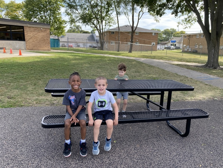 kids sitting in a picnic table on the playground 