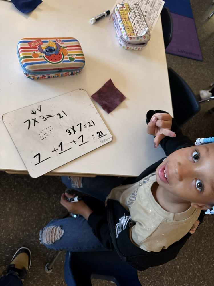 student at table working on a whiteboard 