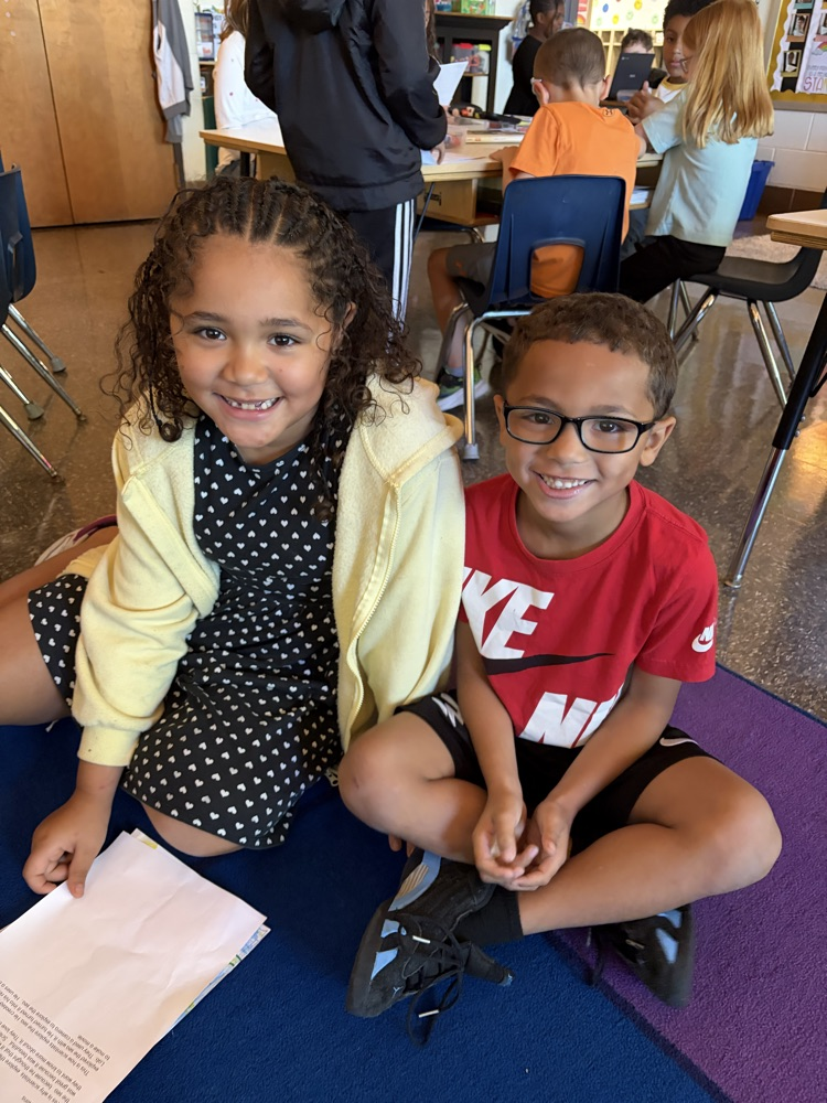 two students on the carpet reading essays